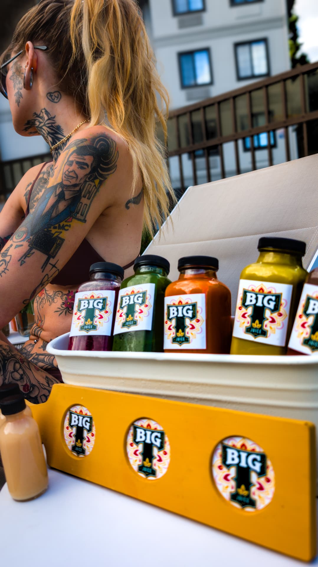 A close-up of colorful BIG T Juice bottles at a sunny poolside gathering