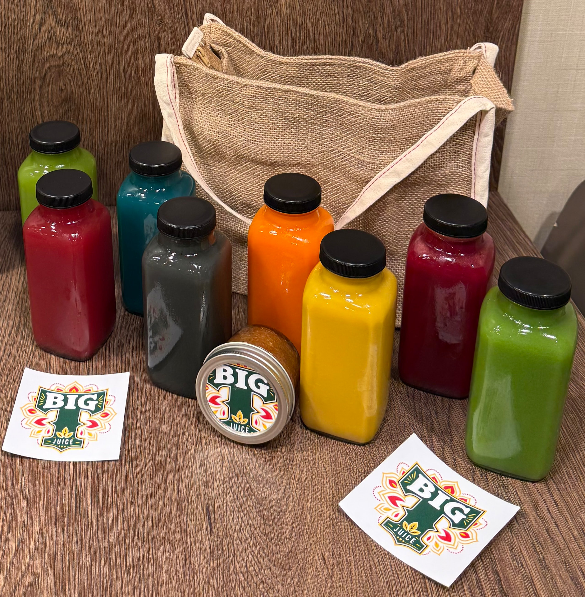 A multi-bottle BIG T Juice pack lined up with a jute tote